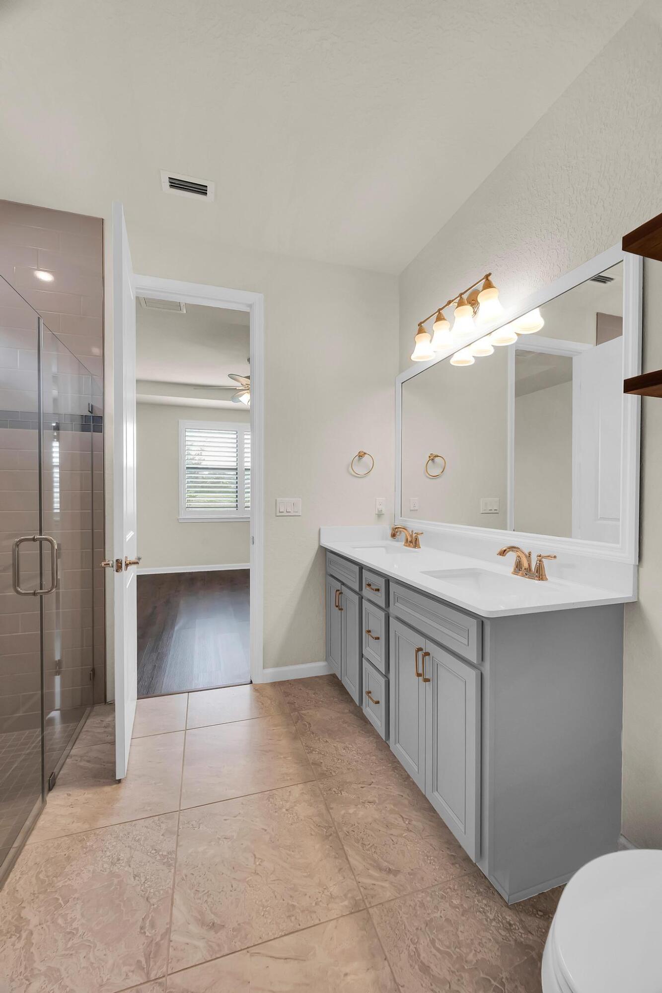 680 Southeast Villandry Way Port St. Lucie, FL 34984 - Photo 10 of 38 a spacious bathroom with a double vanity sink mirror and toilet