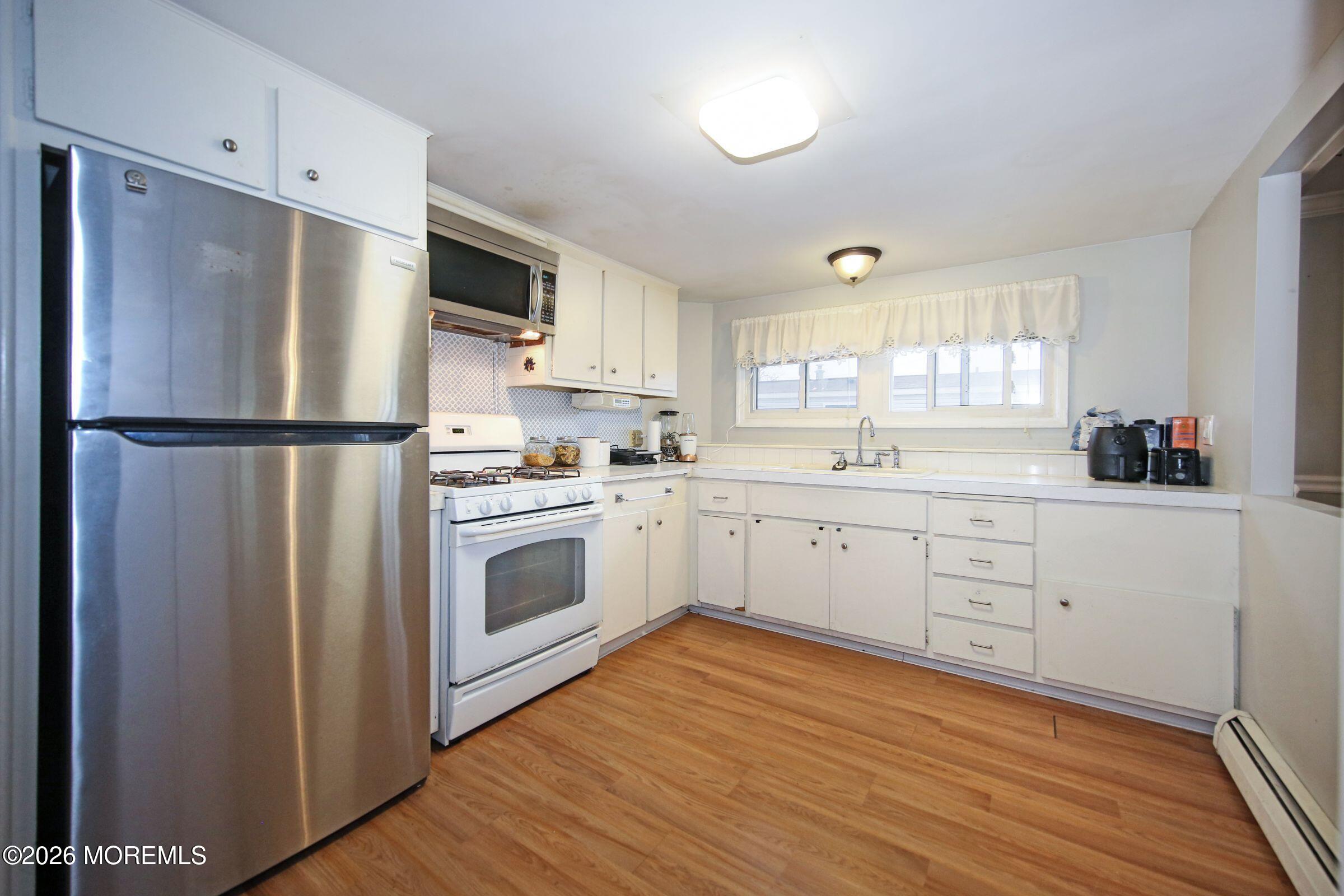 14 Monique Circle Hazlet, NJ 07730 - Photo 9 of 23 a kitchen with white cabinets stainless steel appliances a sink and a window