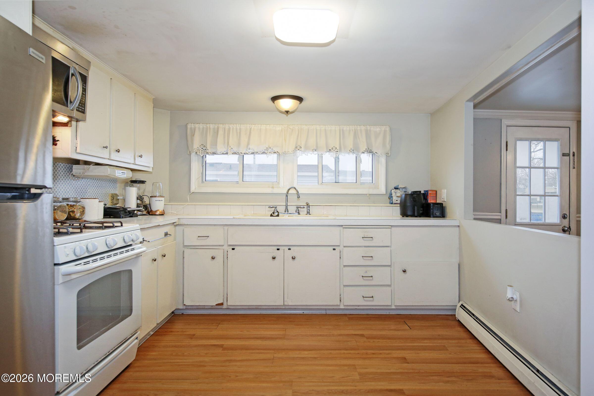 14 Monique Circle Hazlet, NJ 07730 - Photo 10 of 23 a kitchen with white cabinets appliances and a window