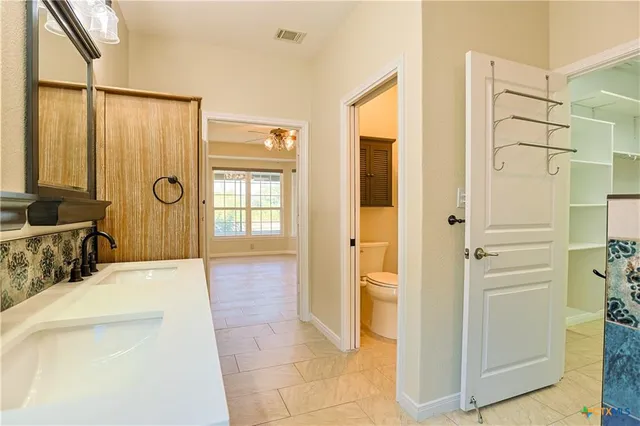 a en suite bathroom with a granite countertop sink a mirror a bathtub and next to a window