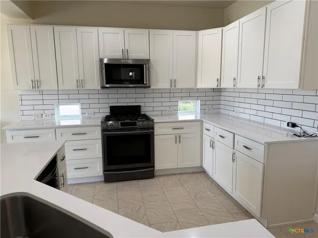 a kitchen with white cabinets and black appliances