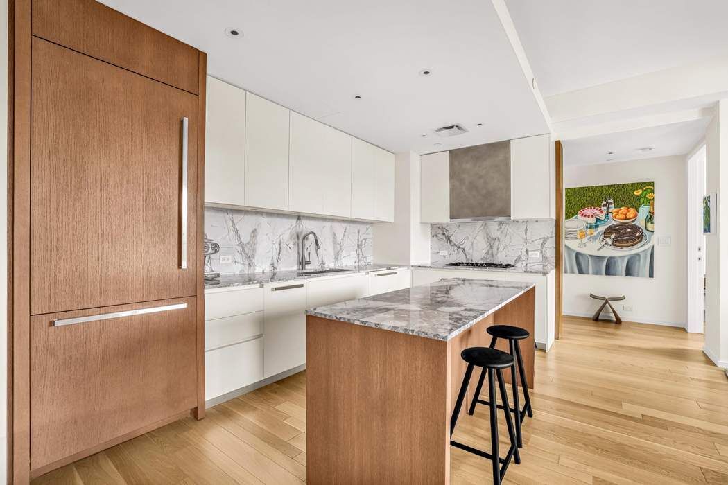 75 Kenmare Street, Unit 6B Manhattan, NY 10012 - Photo 4 of 11 a kitchen with stainless steel appliances granite countertop a refrigerator a sink and a stove with wooden floor