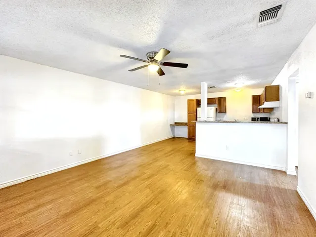 a view of a kitchen with wooden floor and a ceiling fan