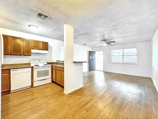 a kitchen with granite countertop wooden floors and white stainless steel appliances