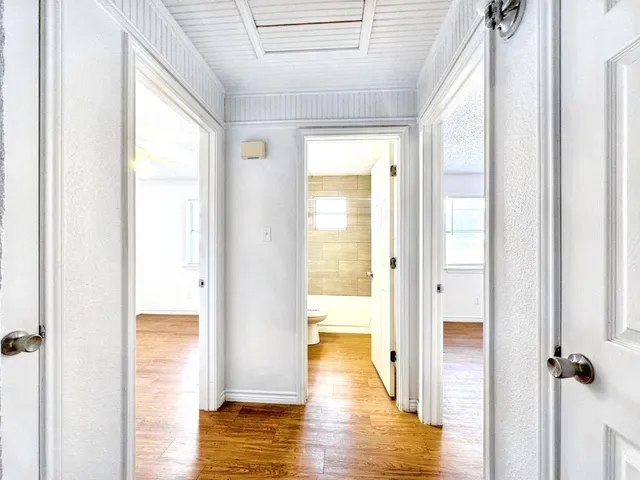 a view of a hallway with wooden floor and a bathroom view