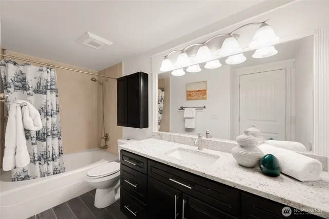 a bathroom with a granite countertop sink a toilet and a large mirror
