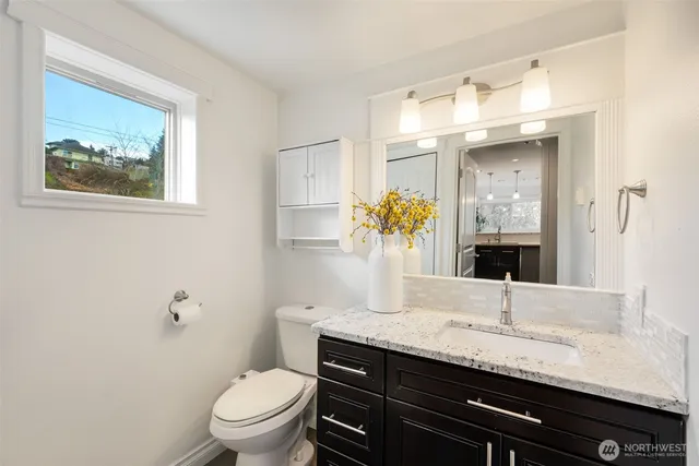 a bathroom with a granite countertop sink a toilet and a mirror