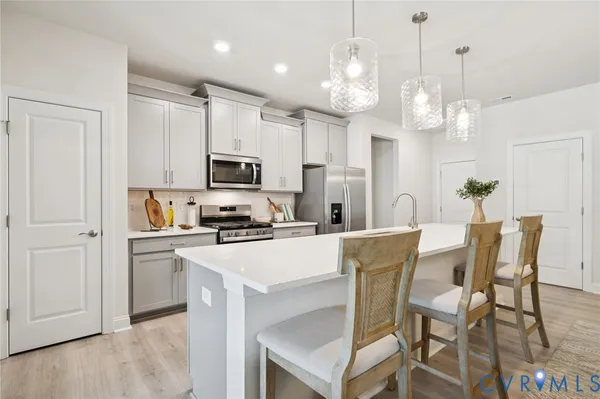 a kitchen with stainless steel appliances granite countertop a dining table chairs refrigerator and microwave