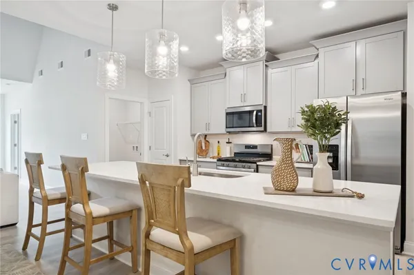 a kitchen with stainless steel appliances granite countertop a dining table chairs sink and microwave