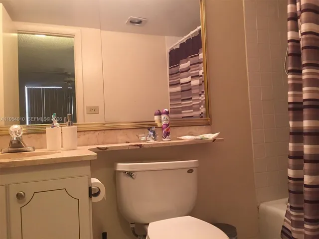 a bathroom with a sink a toilet and shower curtain