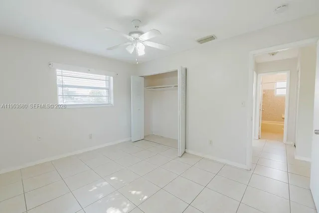 a view of an empty room with window and chandelier fan