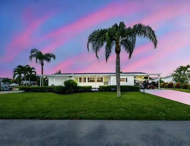 a view of a house with a big yard and a large trees