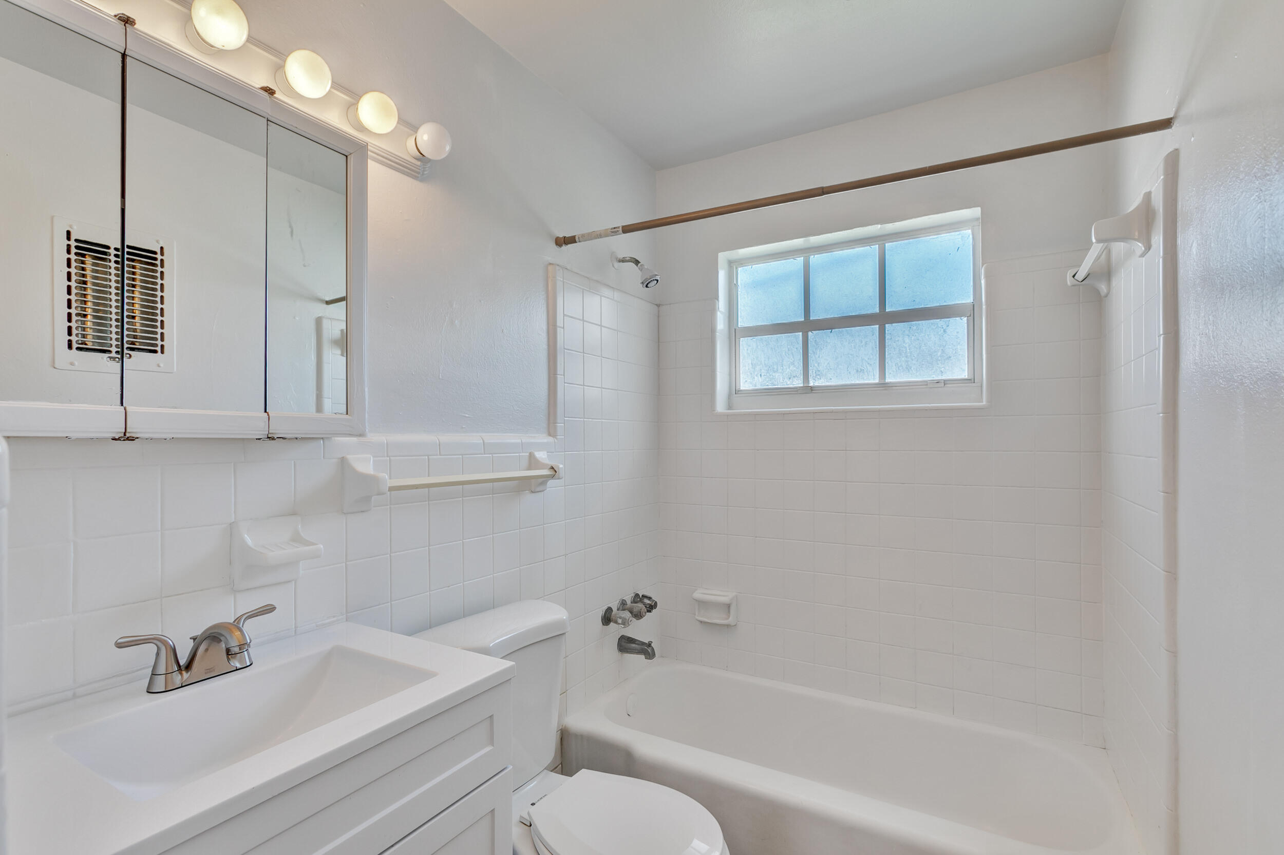 461 Silver Beach Road, Unit 1 Riviera Beach, FL 33403 - Photo 30 of 33 a bathroom with a bathtub shower sink vanity and toilet