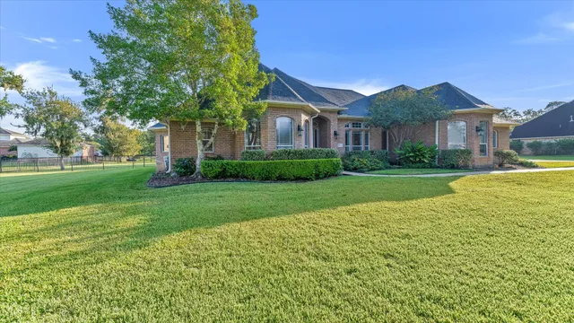 a view of house in front of a big yard with large trees