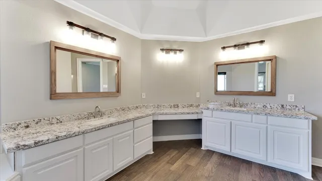 a bathroom with a granite countertop sink double and mirror wooden cabinet
