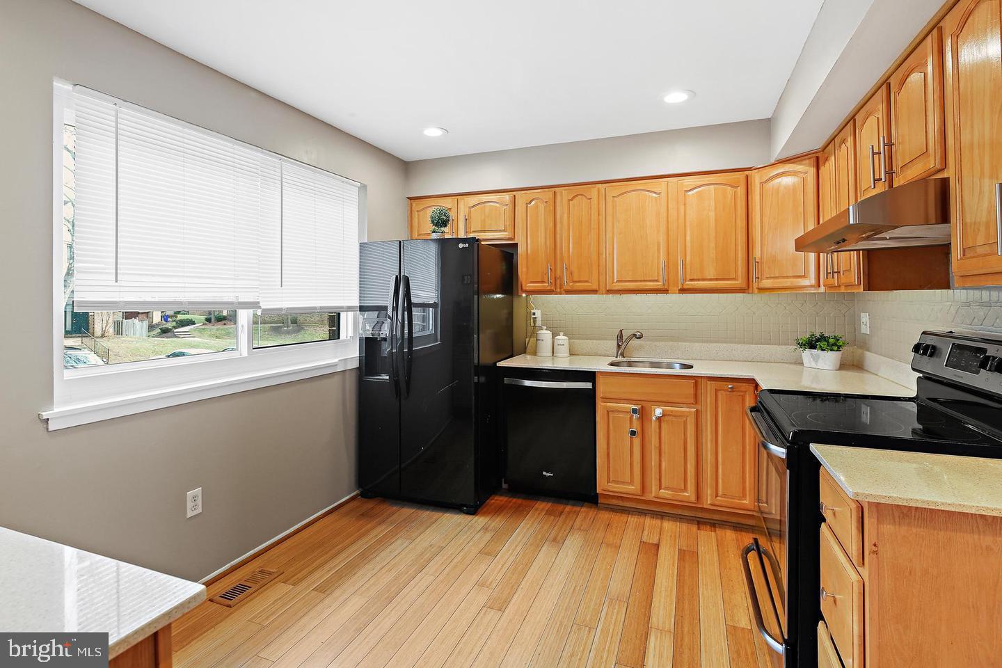 7068 Winter Rose Path Columbia, MD 21045 - Photo 5 of 30 a kitchen with stainless steel appliances granite countertop a refrigerator a sink dishwasher and wooden cabinets with wooden floor