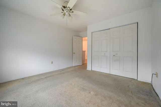 an empty room with windows and chandelier fan