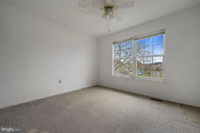 a view of an empty room with a window and a kitchen