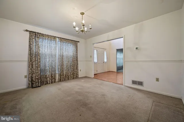 a view of a livingroom with a chandelier fan and windows