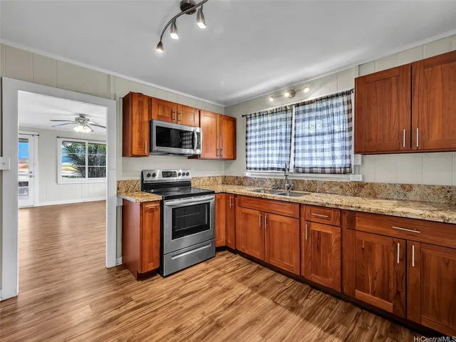 a kitchen with granite countertop wooden floors stainless steel appliances a sink and a window
