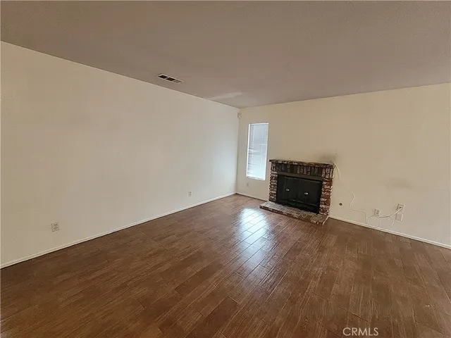 an empty room with wooden floor and fireplace