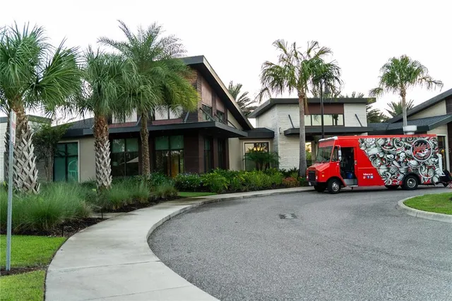 a front view of a house with a yard and palm trees