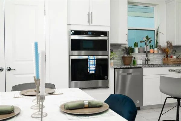 a kitchen with granite countertop white cabinets and stainless steel appliances