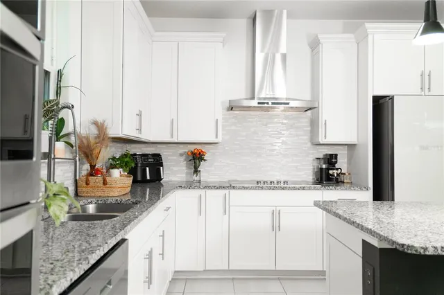 a kitchen with stainless steel appliances granite countertop a sink a stove and white cabinets
