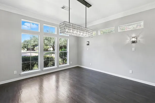 a view of a room with wooden floor chandelier and windows