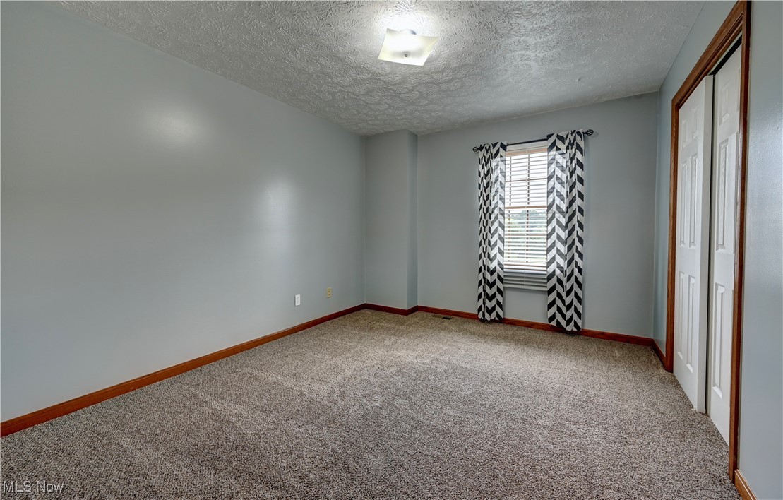 9559 Trail Bottom Road Northwest Dundee, OH 44624 - Photo 25 of 48 Unfurnished bedroom with carpet, a textured ceiling, and a closet