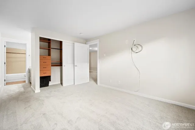 a view of an empty room with closet and a window
