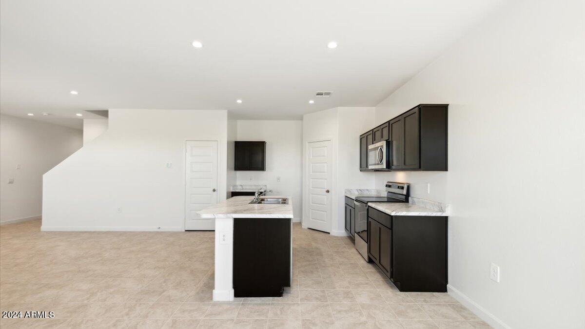 2077 West Sentiero Avenue Apache Junction, AZ 85120 - Photo 9 of 24 a living room with stainless steel appliances kitchen island granite countertop a sink and a stove top oven with wooden floor