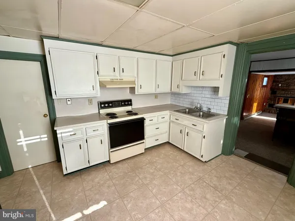 a kitchen with stainless steel appliances a stove a sink and white cabinets