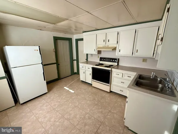 a kitchen with furniture a refrigerator and a stove top oven