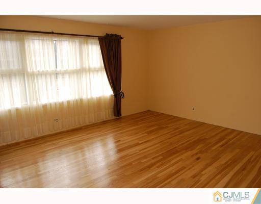 91 Princeton Road Old Bridge, NJ 08859 - Photo 4 of 9 an empty room with wooden floor and windows