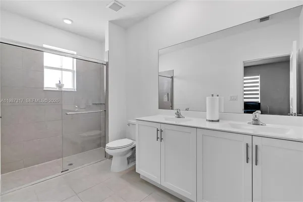 a bathroom with a double vanity sink toilet and shower