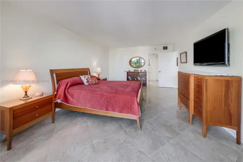 a bedroom with a bed and a flat tv screen on dresser