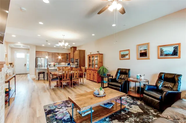 a living room with furniture kitchen view and a wooden floor