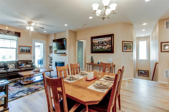 a kitchen with stainless steel appliances kitchen island granite countertop a refrigerator a stove a sink dishwasher with a dining table and chairs with wooden floor