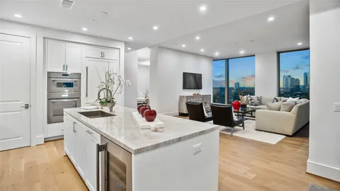 a open kitchen with stainless steel appliances kitchen island granite countertop a refrigerator a sink dishwasher and a flat screen tv