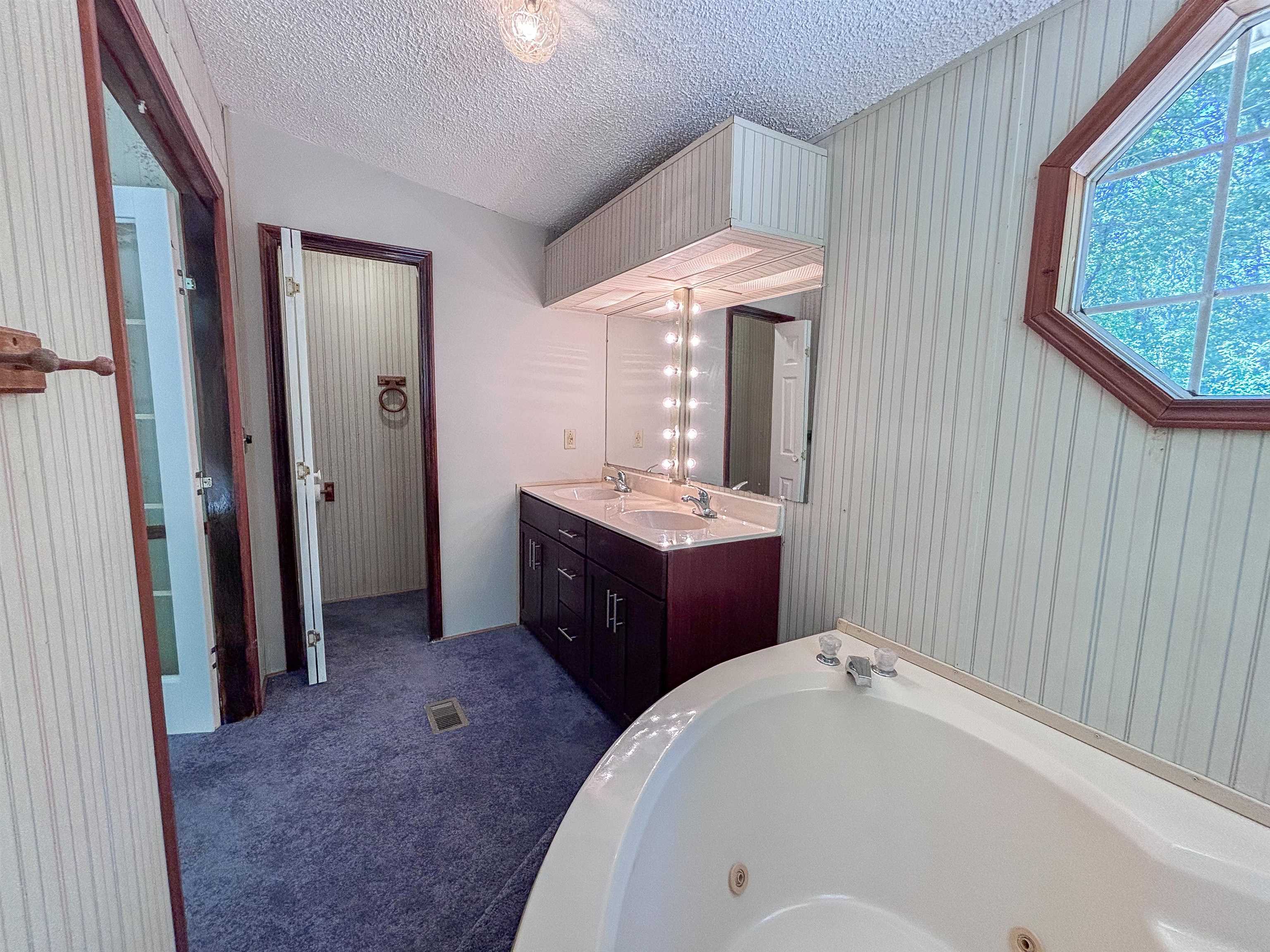 471 Milton Road Millington, TN 38053 - Photo 25 of 30 Spa-inspired primary bathroom featuring a soaking tub, dual-sink vanity with illuminated mirror and ample storage, neutral tile flooring, and abundant natural light from corner windows