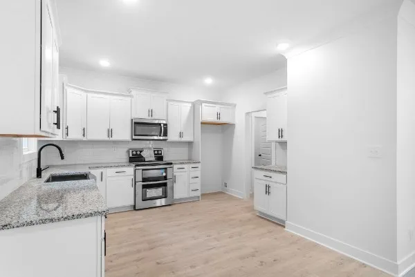 a kitchen with granite countertop a refrigerator stove and sink