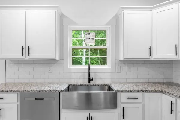a kitchen with granite countertop a sink and white cabinets