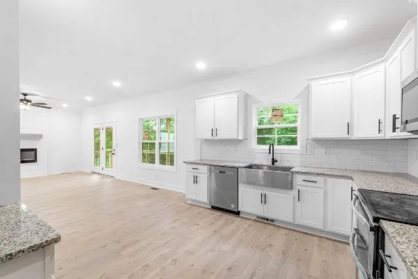 a large kitchen with granite countertop a stove top oven a sink a dining table and chairs