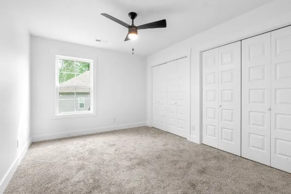 an empty room with a ceiling fan and a window