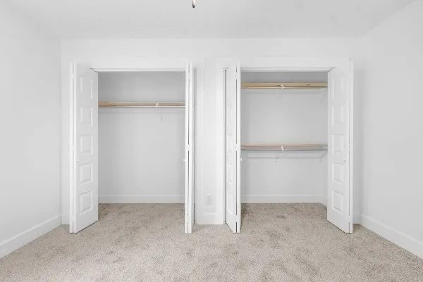a view of an empty room with closet and a bathroom