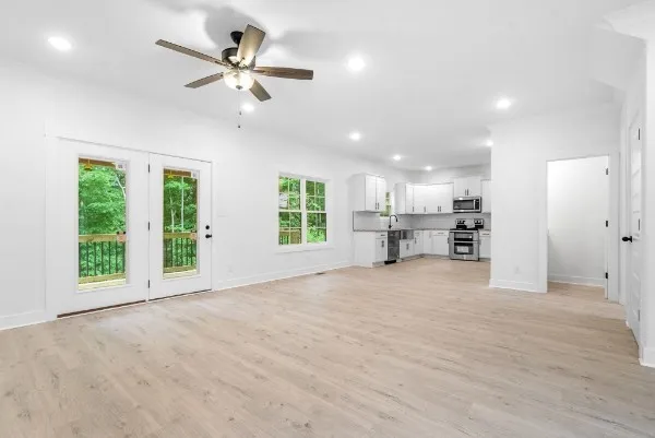 a view of an empty room with a window and a kitchen