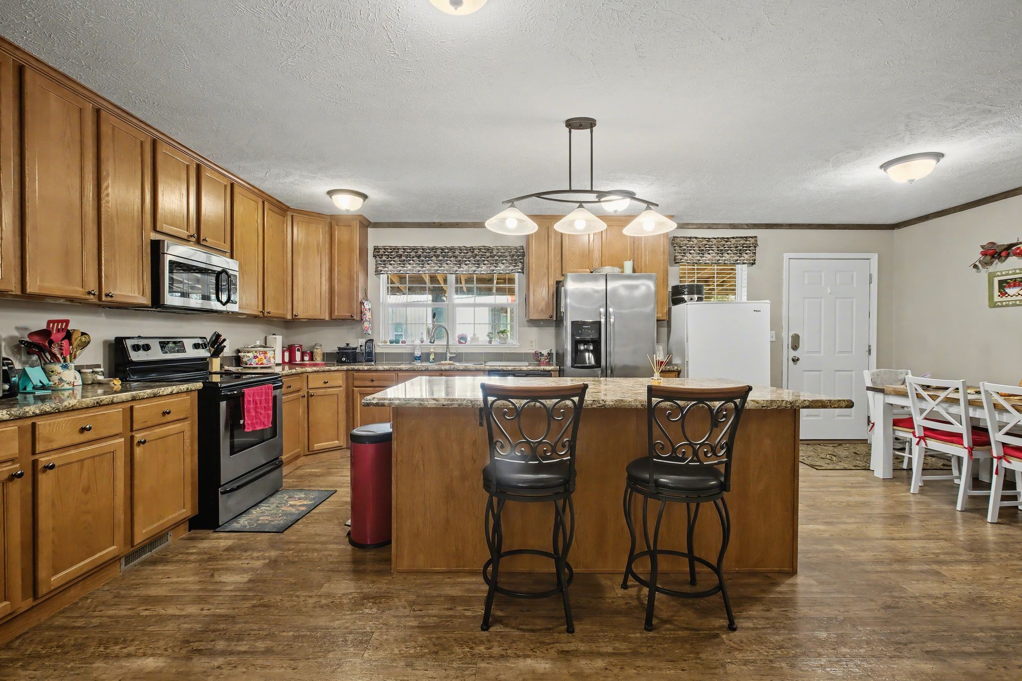 10878 Highway 7 Primm Springs, TN 38476 - Photo 21 of 37 a kitchen with stainless steel appliances granite countertop a stove a sink a dining table and chairs with wooden floor