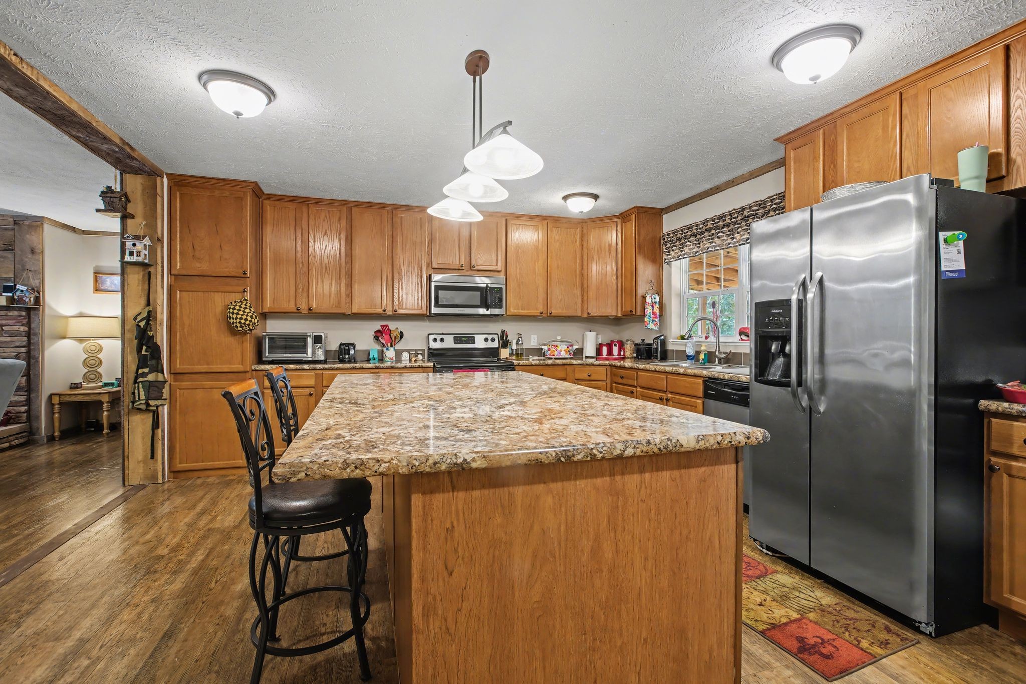 10878 Highway 7 Primm Springs, TN 38476 - Photo 22 of 37 a kitchen with stainless steel appliances granite countertop a refrigerator a oven a sink with island and chairs