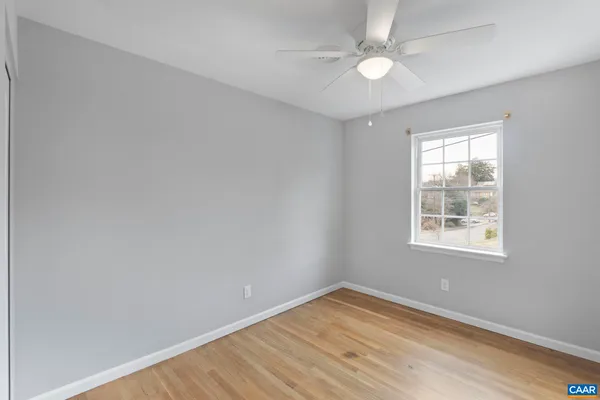 a view of an empty room with a window and wooden floor